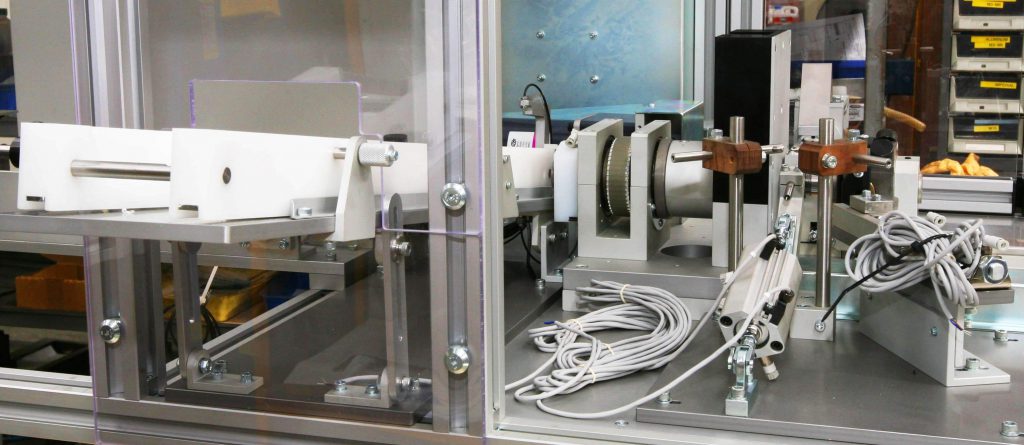 Custom automated machinery setup with precision components, wiring, and safety enclosures in a workshop.